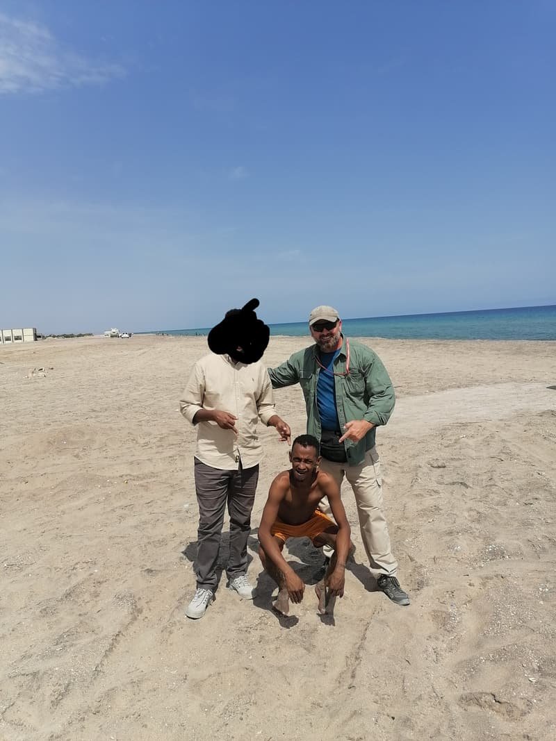 On the shore with two local men