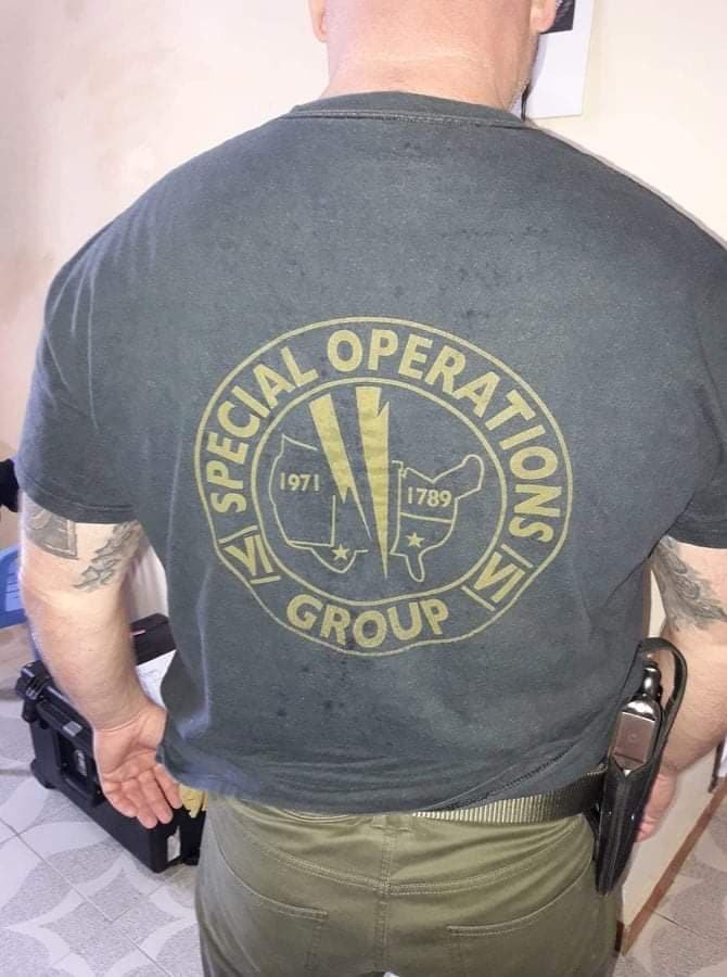 A team member seen from behind, unit insignia on his shirt