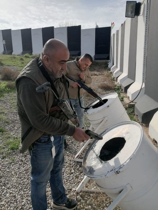 Two men handling equipment beside a vehicle